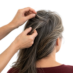 Hands parting a woman's hair to look at her scalp